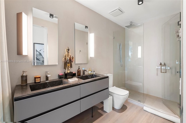full bath featuring vanity, toilet, a stall shower, visible vents, and wood finished floors