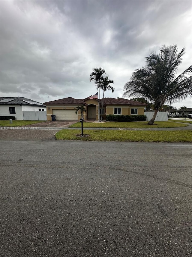 view of front of home featuring a front yard, stucco siding, fence, an attached garage, and a tiled roof