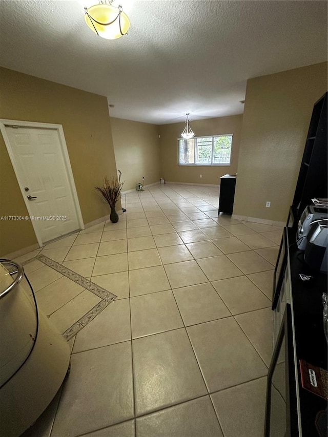 empty room featuring light tile patterned flooring, baseboards, and a textured ceiling