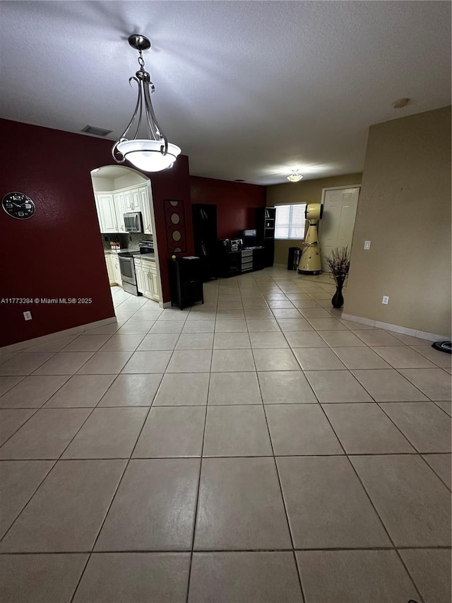 kitchen with light tile patterned flooring, pendant lighting, stainless steel appliances, visible vents, and white cabinets