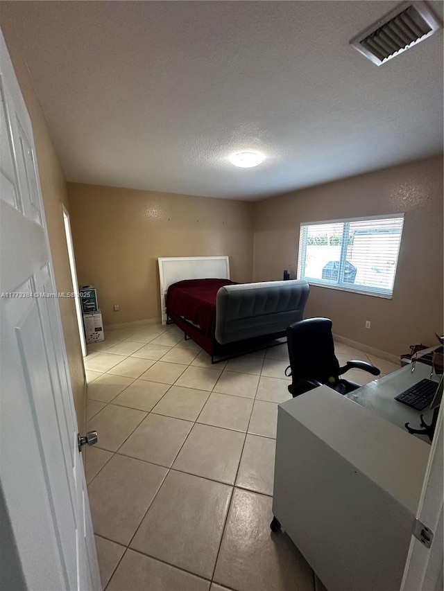 bedroom with light tile patterned floors, a textured ceiling, baseboards, and visible vents