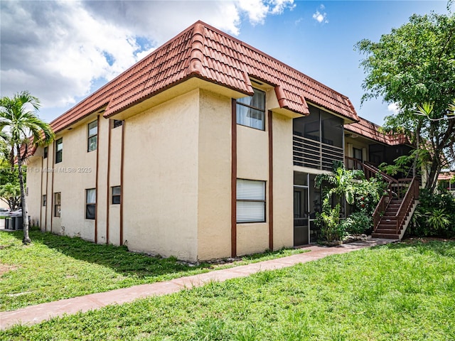 6545 W 27th Ct Unit 24-47, Hialeah, FL 33016 - view of side of home with stucco siding, mansard roof, a lawn, and stairway