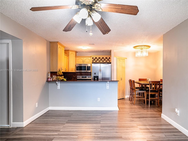 6545 W 27th Ct Unit 24-47, Hialeah, FL 33016 - kitchen featuring stainless steel appliances, dark countertops, a textured ceiling, a peninsula, and wood finished floors