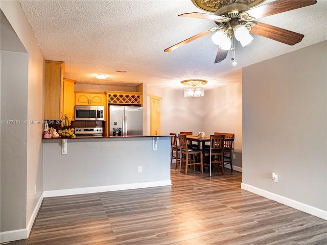 6545 W 27th Ct Unit 24-47, Hialeah, FL 33016 - kitchen featuring stainless steel appliances, dark countertops, light wood-style floors, a textured ceiling, and a peninsula