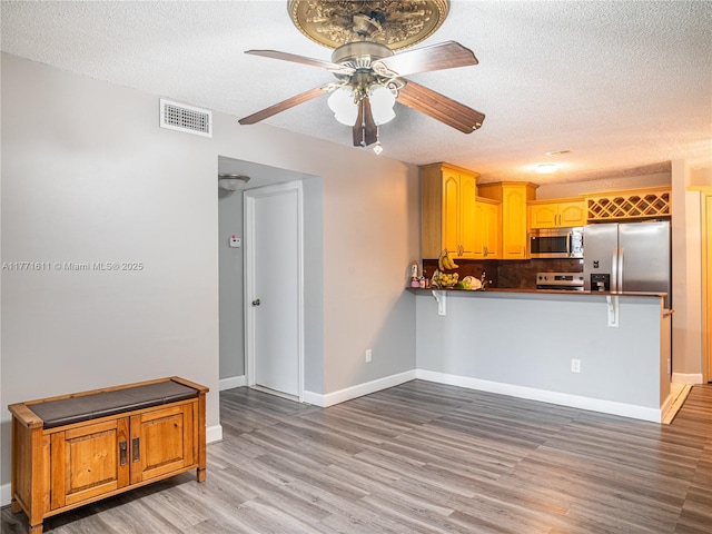 6545 W 27th Ct Unit 24-47, Hialeah, FL 33016 - kitchen with appliances with stainless steel finishes, a textured ceiling, ceiling fan, light wood-style flooring, and a peninsula
