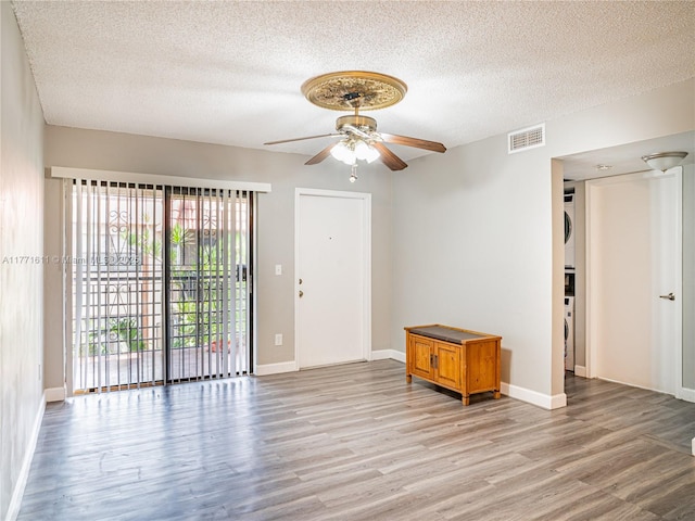 6545 W 27th Ct Unit 24-47, Hialeah, FL 33016 - spare room with stacked washing machine and dryer, a ceiling fan, a textured ceiling, and light wood finished floors