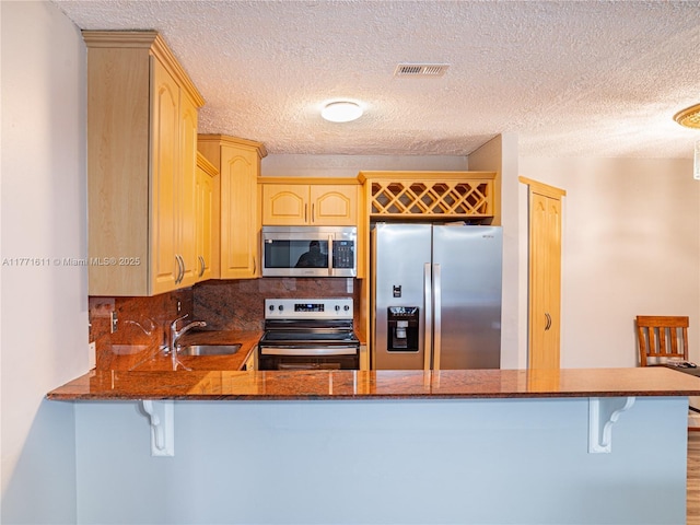 6545 W 27th Ct Unit 24-47, Hialeah, FL 33016 - kitchen featuring appliances with stainless steel finishes, light brown cabinetry, backsplash, a textured ceiling, and a peninsula