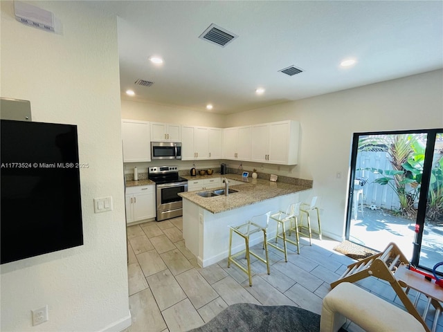 764 NE 206th Ter, Miami, FL 33179 - kitchen with visible vents, a peninsula, a breakfast bar, appliances with stainless steel finishes, and a sink