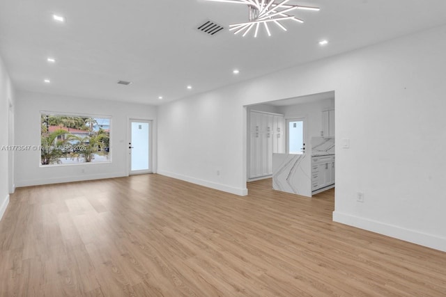unfurnished living room featuring baseboards, visible vents, and light wood-type flooring