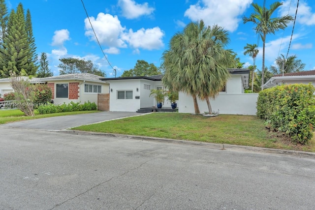 ranch-style home with driveway, a front yard, and stucco siding