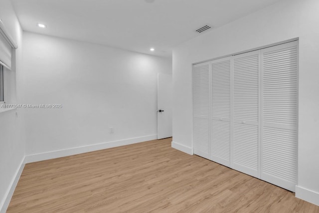 unfurnished bedroom featuring light wood-style flooring, recessed lighting, baseboards, visible vents, and a closet