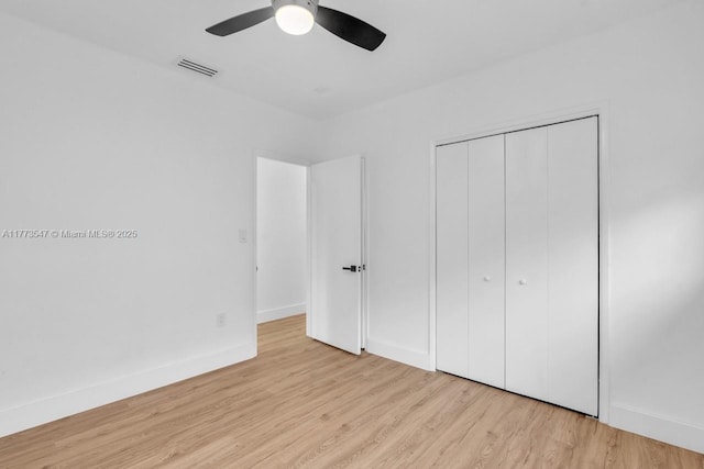 unfurnished bedroom with baseboards, a closet, wood finished floors, and visible vents