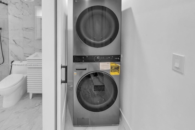 laundry room featuring stacked washer and clothes dryer and marble finish floor