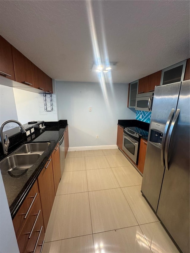 1800 N Bayshore Dr Unit 1404, Miami, FL 33132 - kitchen with stainless steel appliances, a sink, baseboards, light tile patterned flooring, and dark stone countertops