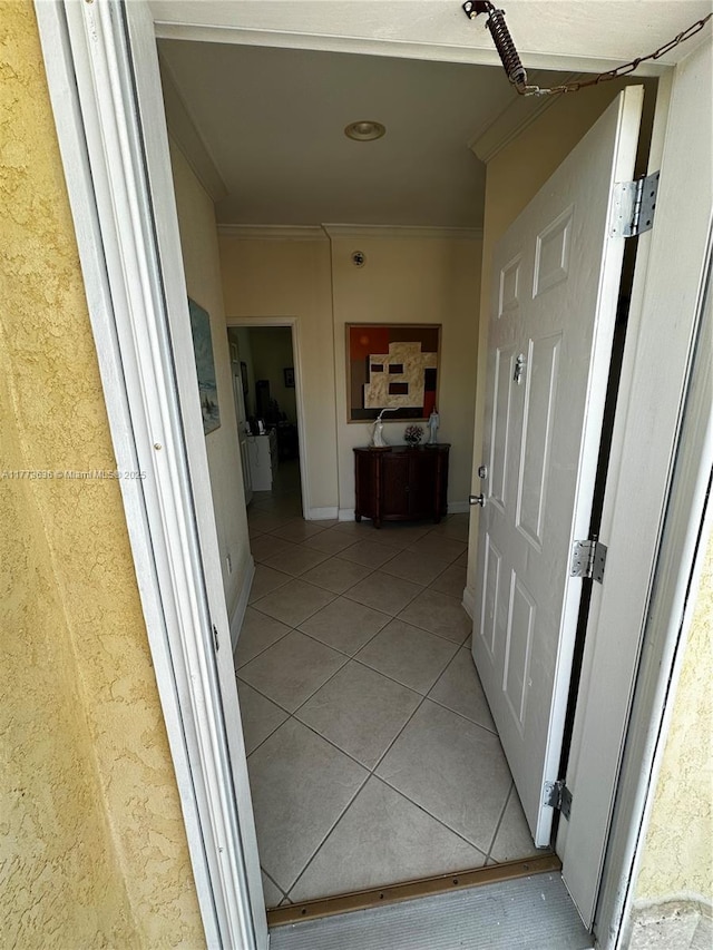 hallway with light tile patterned floors, crown molding, and baseboards