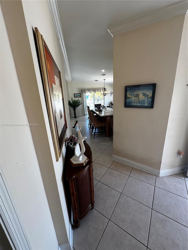 hall featuring baseboards, crown molding, and tile patterned flooring