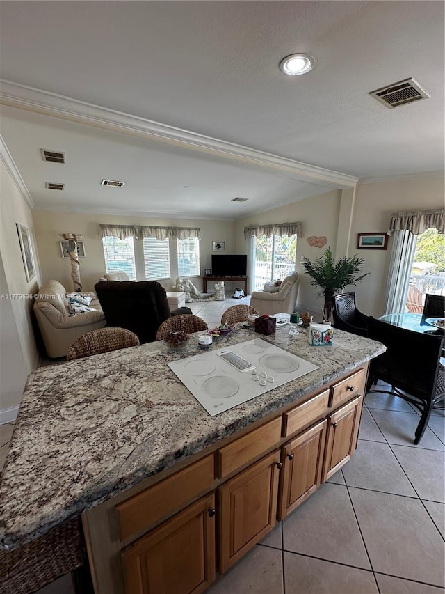 kitchen with open floor plan, ornamental molding, white electric cooktop, light tile patterned flooring, and light stone counters