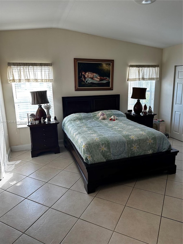 bedroom with baseboards, vaulted ceiling, and light tile patterned floors