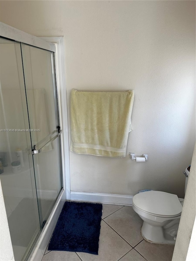 full bathroom with tile patterned floors, toilet, baseboards, and a shower stall