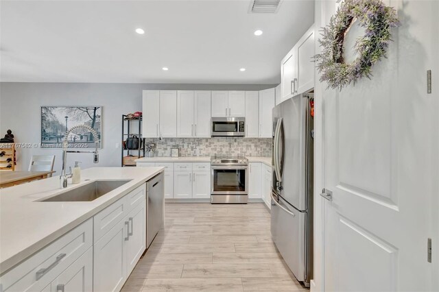709 SW 17th St, Fort Lauderdale, FL 33315 - kitchen with a sink, white cabinetry, backsplash, light countertops, and appliances with stainless steel finishes