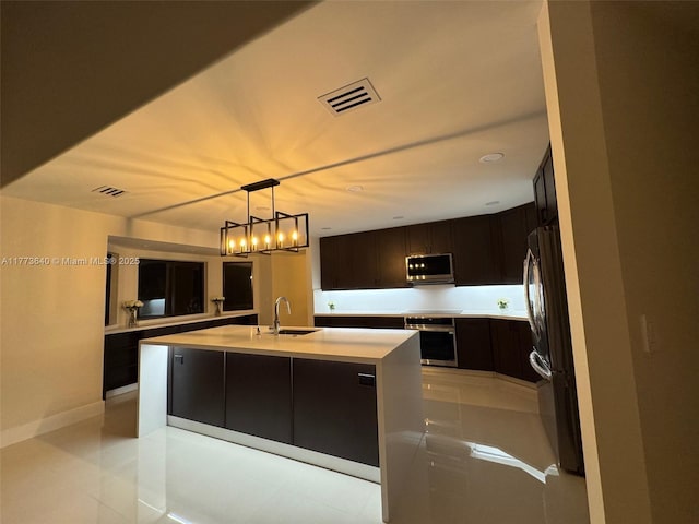 20160 NW 9th Dr, Pembroke Pines, FL 33029 - kitchen featuring stainless steel appliances, light countertops, a center island with sink, light tile patterned floors, and dark brown cabinets
