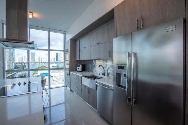3131 NE 188th St Unit 2-1002, Aventura, FL 33180 - kitchen featuring appliances with stainless steel finishes, a sink, decorative backsplash, light countertops, and island exhaust hood