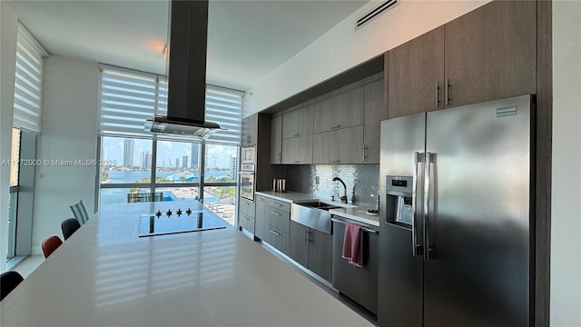3131 NE 188th St Unit 2-1002, Aventura, FL 33180 - kitchen with appliances with stainless steel finishes, a sink, light countertops, decorative backsplash, and island exhaust hood