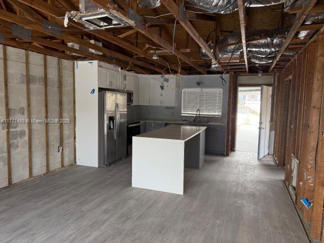 kitchen with a sink, a kitchen island, appliances with stainless steel finishes, light wood-style flooring, and white cabinets