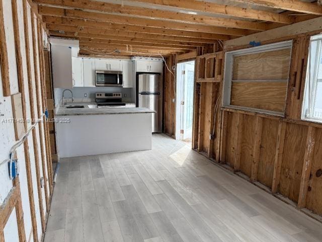 kitchen featuring light countertops, a sink, white cabinets, a peninsula, and appliances with stainless steel finishes