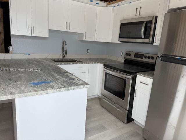 kitchen with white cabinetry, a sink, and stainless steel appliances