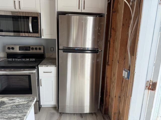 kitchen with white cabinets, stainless steel appliances, and light stone counters