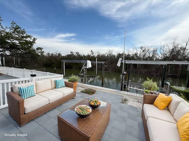 view of patio featuring a water view, an outdoor living space, boat lift, and a dock