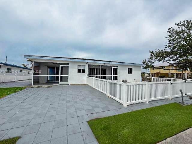 back of house featuring a patio area, stucco siding, a sunroom, and fence