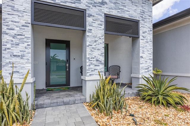view of exterior entry with stucco siding and stone siding