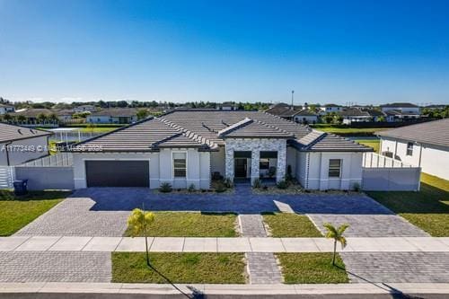 view of front of house featuring a garage, decorative driveway, stucco siding, a tiled roof, and a residential view