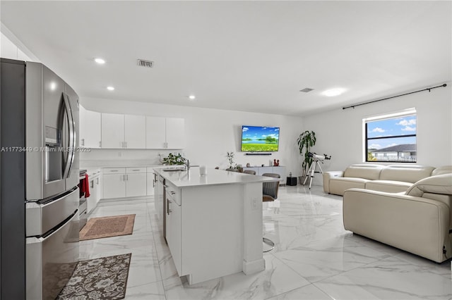 kitchen with appliances with stainless steel finishes, open floor plan, marble finish floor, recessed lighting, and an island with sink