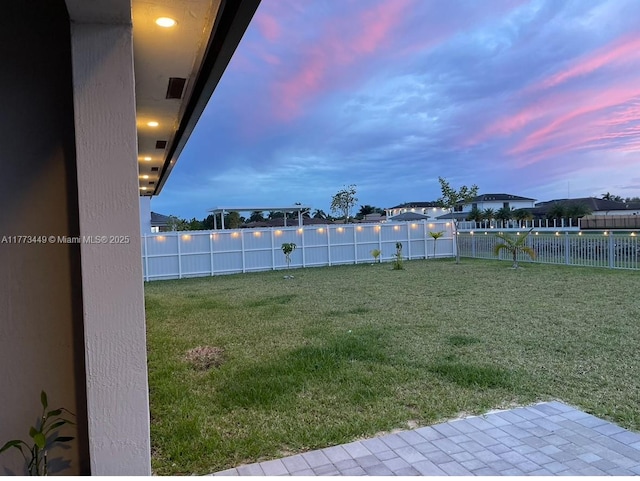 yard at dusk with a fenced backyard and visible vents