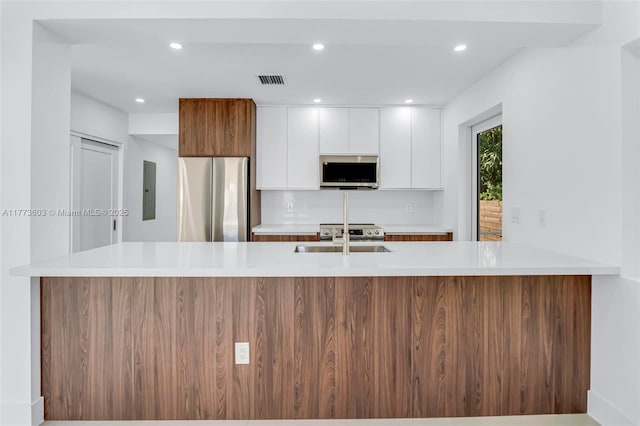 kitchen with light countertops, recessed lighting, a sink, white cabinets, and appliances with stainless steel finishes