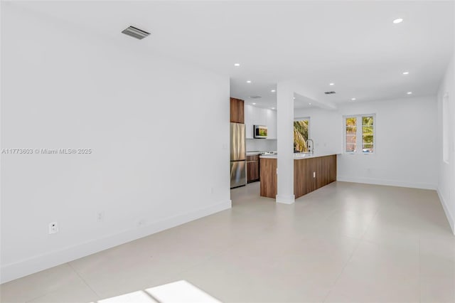 unfurnished living room featuring baseboards, visible vents, and recessed lighting