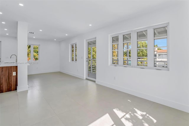 empty room featuring visible vents, a sink, baseboards, and recessed lighting