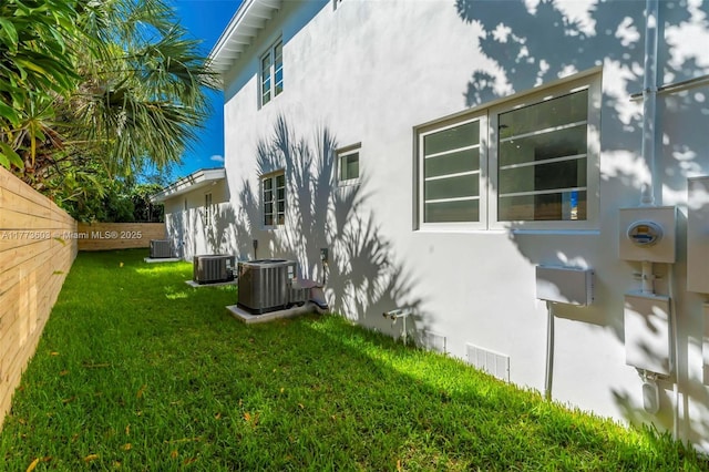 view of home's exterior with stucco siding, cooling unit, and a yard
