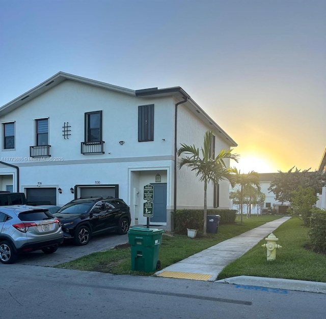 view of front of home with driveway, stucco siding, an attached garage, and a yard