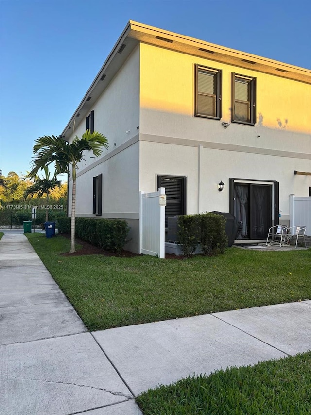 exterior space with stucco siding and a yard
