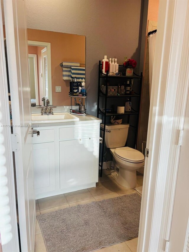 bathroom featuring a textured ceiling, toilet, tile patterned flooring, and vanity