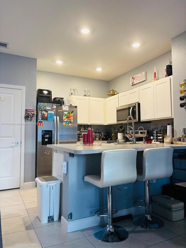 kitchen with light countertops, white cabinets, stainless steel appliances, and a breakfast bar