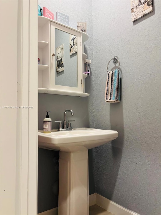 bathroom featuring a sink, baseboards, and a textured wall