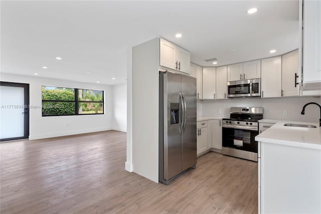 601 NW 35th Ter, Lauderhill, FL 33311 - kitchen featuring light wood finished floors, stainless steel appliances, white cabinets, a sink, and open floor plan