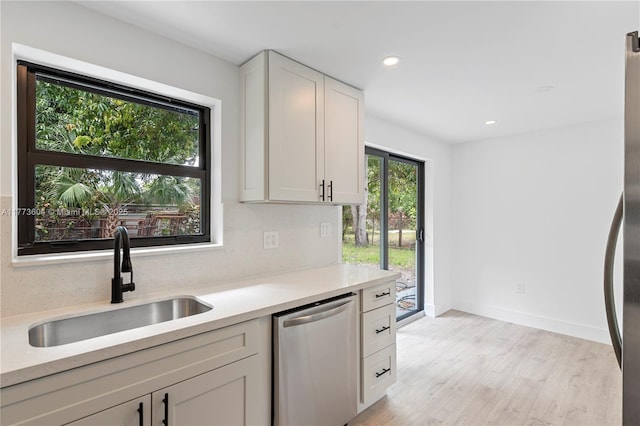 601 NW 35th Ter, Lauderhill, FL 33311 - kitchen with white cabinets, light countertops, a sink, light wood-type flooring, and dishwasher