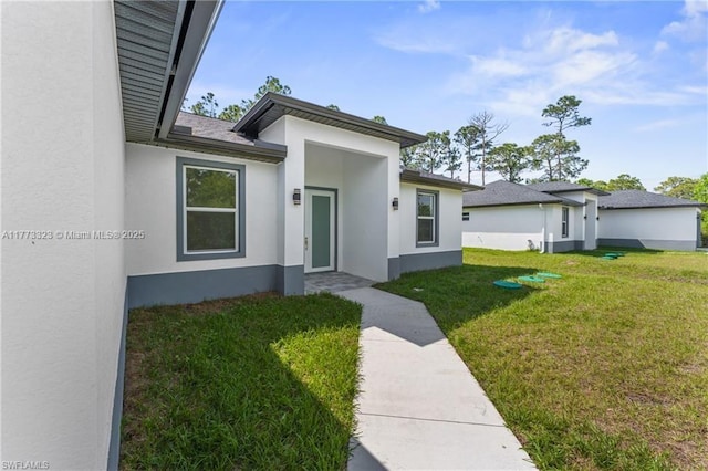 property entrance with a lawn and stucco siding