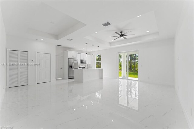 empty room featuring a tray ceiling, recessed lighting, marble finish floor, visible vents, and a ceiling fan